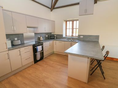 A kitchen with cabinets oven microwave toaster and bar stools at The Granary in Prussia Cove near Rosudgeon