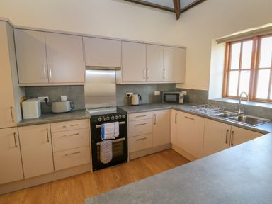 A kitchen with cabinets a stove a sink a microwave toaster and a kettle at The Granary in Prussia Cove near Rosudgeon