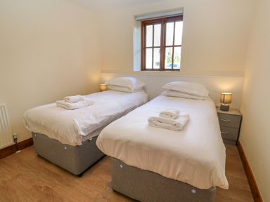 A bedroom with two single beds with white bedding and towels on each bed at The Granary in Prussia Cove near Rosudgeon
