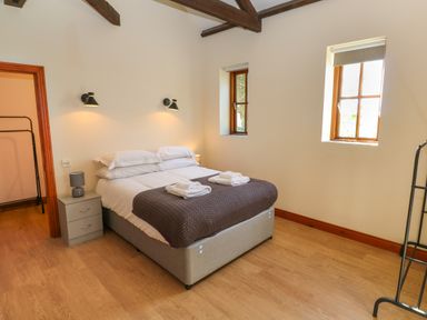 A bedroom with a double bed side tables lamps two windows and wooden floor at The Granary in Prussia Cove near Rosudgeon