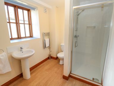A bathroom with a sink towel holder window toilet and shower at The Granary Prussia Cove near Rosudgeon