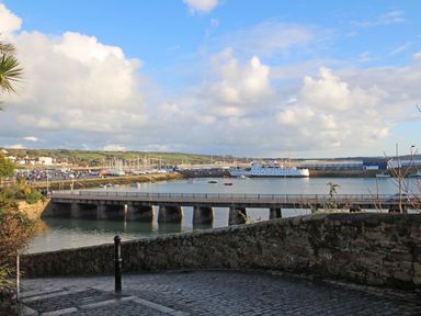 A coastal view with a bridge over water boats in a harbour and buildings in the background at The Granary in Prussia Cove near Rosudgeon