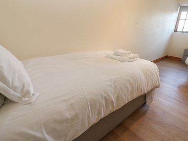 A bedroom with a single bed linens and folded towels near a window at The Granary in Prussia Cove near Rosudgeon