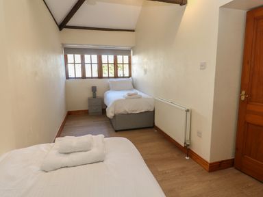 A bedroom with two single beds a nightstand and window at The Granary in Prussia Cove near Rosudgeon