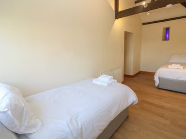 A bedroom with two single beds and folded towels on each at The Granary in Prussia Cove near Rosudgeon
