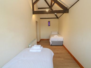 A narrow bedroom with two single beds and exposed wooden beams at The Granary Prussia Cove near Rosudgeon