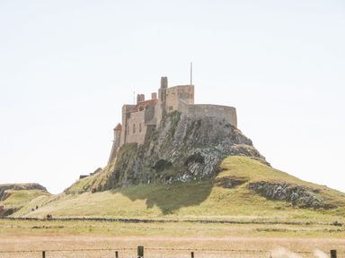 A castle situated on a rocky hill surrounded by grassland at Bruno's Bothy in Middleton near Belford