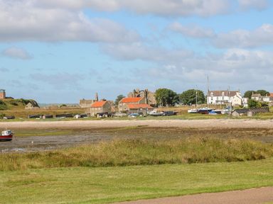 A coastal village with boats on shore and stone buildings with red roofs at Bruno's Bothy in Middleton near Belford
