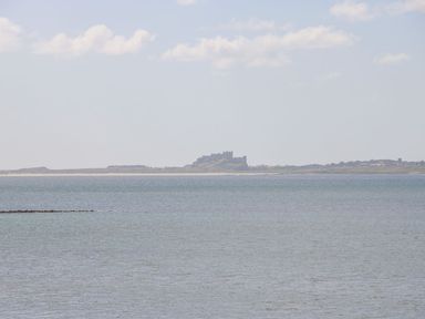 A large body of water with a castle on the distant shoreline at Bruno's Bothy in Middleton near Belford