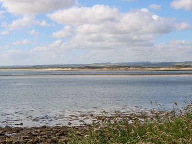 A coastal view with water sand dunes and grassy foreground at Brunos Bothy in Middleton near Belford