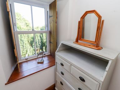 A bedroom with a window and a mirror at Bruno's Bothy Middleton near Belford