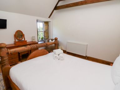 A bedroom with a wooden bed and dresser at Bruno's Bothy Middleton near Belford