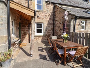 An outdoor seating area with a table and chairs at Bruno's Bothy Middleton near Belford