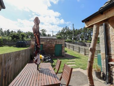 A garden with a table and chairs at Bruno's Bothy Middleton near Belford