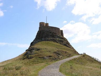 A castle on top of a rocky hill with a cobblestone path leading up to it