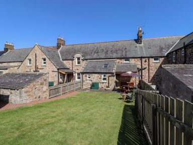 A garden area with cottages and outdoor furniture at Kits Cottage Middleton near Belford