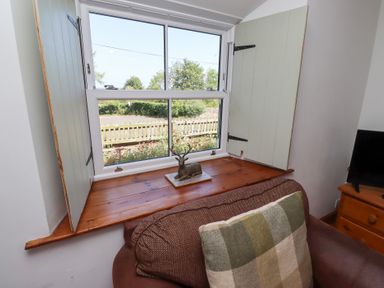 A living room with a window seat and decorative item at Kits Cottage Middleton near Belford