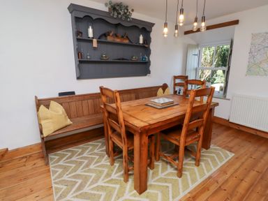 A dining room with a wooden table and chairs at Kits Cottage Middleton near Belford