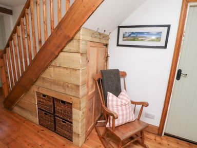 A hallway with a rocking chair and storage baskets at Kits Cottage Middleton near Belford