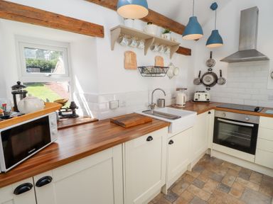 A kitchen with a sink and microwave at Kits Cottage in Middleton near Belford