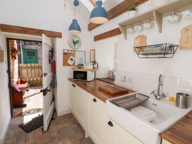 A kitchen with a sink and microwave at Kits Cottage in Middleton near Belford