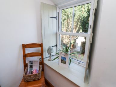 A corner with a chair, a plant, and a window at Kits Cottage Middleton near Belford