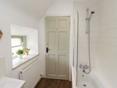 A bathroom with a bathtub and sink at Kits Cottage Middleton near Belford