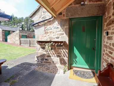 An entrance area with a green door and stone wall at Kits Cottage in Middleton near Belford