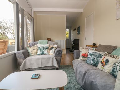 A living room with two sofas decorated with animal and farm themed pillows and a white coffee table at Y Goedlan in Tywyn