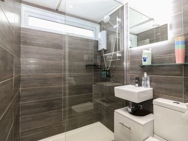 A bathroom with a walk-in shower sink toilet and a mirrored cabinet at Y Goedlan in Tywyn