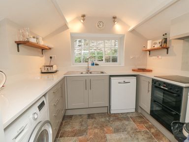 A kitchen with sink and window above dishwasher washing machine toaster and oven at York House in Thornton Dale