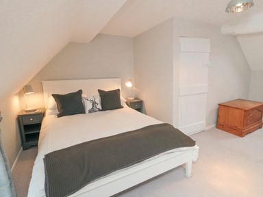 A bedroom with a white bed frame two bedside tables with lamps and a wooden chest at York House in Thornton Dale