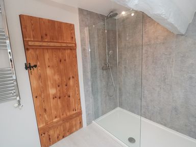 A bathroom with a wooden door a glass enclosed shower area and chrome shower fixtures at York House in Thornton Dale