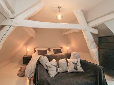 A bedroom with a bed lamps pillows a dark sofa and a chest of drawers at York House in Thornton Dale