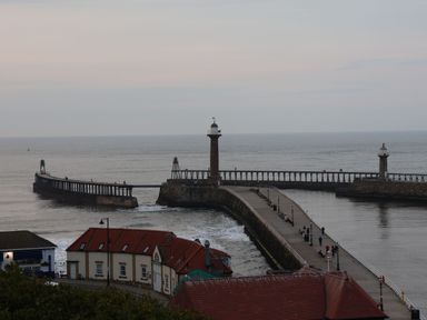 A coastal pier with two lighthouses and buildings nearby at York House in Thornton Dale