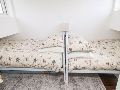 A bedroom with two single beds with patterned bedding and a small lamp in between at Quarry Cottage in Bethesda