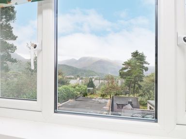 A window showing a view of rooftops trees and mountains at Quarry Cottage in Bethesda