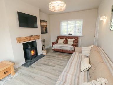 A living room with a fireplace a mounted television two sofas and a window at Ocean Spray in Scarborough