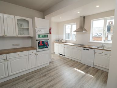 A kitchen with white cabinets wooden countertops and appliances at Ocean Spray in Scarborough