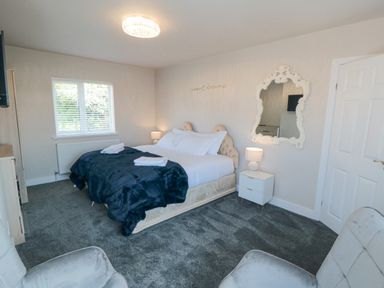A bedroom with a double bed two towels bedside tables with lamps wall mirror and two chairs at Ocean Spray in Scarborough