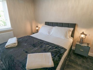 A bedroom with a bed two bedside tables lamps and towels at Ocean Spray in Scarborough