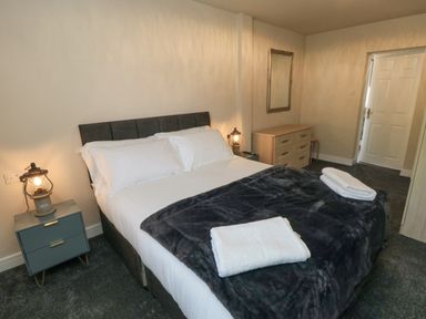 A bedroom with a double bed two bedside tables with lamps a chest of drawers and a mirror at Ocean Spray in Scarborough