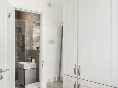 A bathroom with a sink and shower visible through an open door next to a white cabinet in a room at Loe Cottage in Porthleven