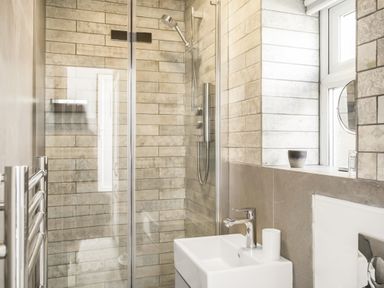 A bathroom with a shower enclosure and a sink with a faucet at Loe Cottage in Porthleven