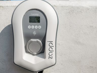 An electric vehicle charging station mounted on a white wall with the brand name zappi visible
