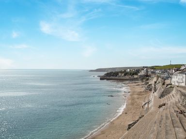 A beach with steps and houses along the shore at Loe Cottage in Porthleven