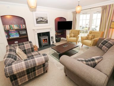 A living room with sofas a coffee table a fireplace a bookshelf and armchairs at The Old Boathouse in Trefin near St Davids