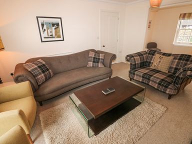 A living room with sofas, armchairs, a coffee table, and a framed picture on the wall at The Old Boathouse in Trefin near St Davids