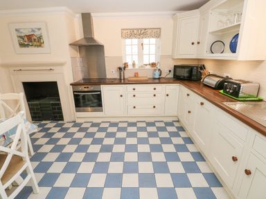 A kitchen with checkered blue and white floor cabinets oven microwave and toaster at The Old Boathouse in Trefin near St Davids