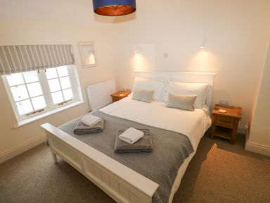 A bedroom with a bed two bedside tables a window and a ceiling light at The Old Boathouse in Trefin near St Davids